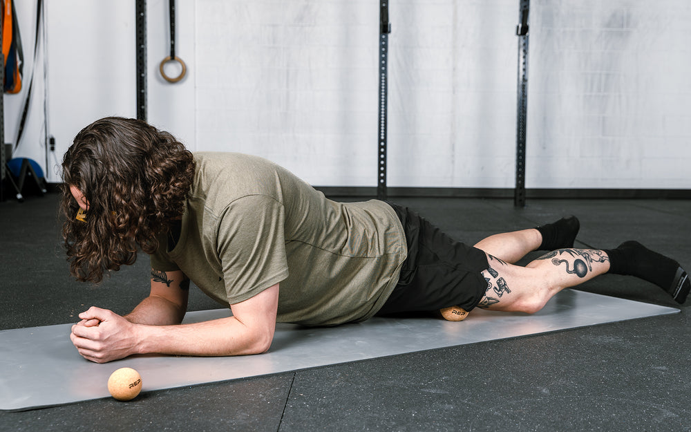 Action-shot: Athlete targeting a pressure point on their leg by rolling the REP Cork Massage Ball against the floor.