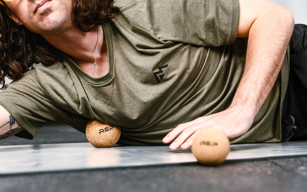 Close-up: Athlete targeting a pressure point on their chest by rolling the REP Cork Massage Ball against the floor.