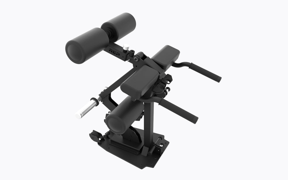A 3/4 view of the REP Leg Curl/Leg Extension Bench Attachment. This angle highlights the Dual-sided weight horns, Integrated band pegs, Adjustable pads, Built-in Side Handles, and Mobility Wheels, and the two lock-pin bench mount attachment points.