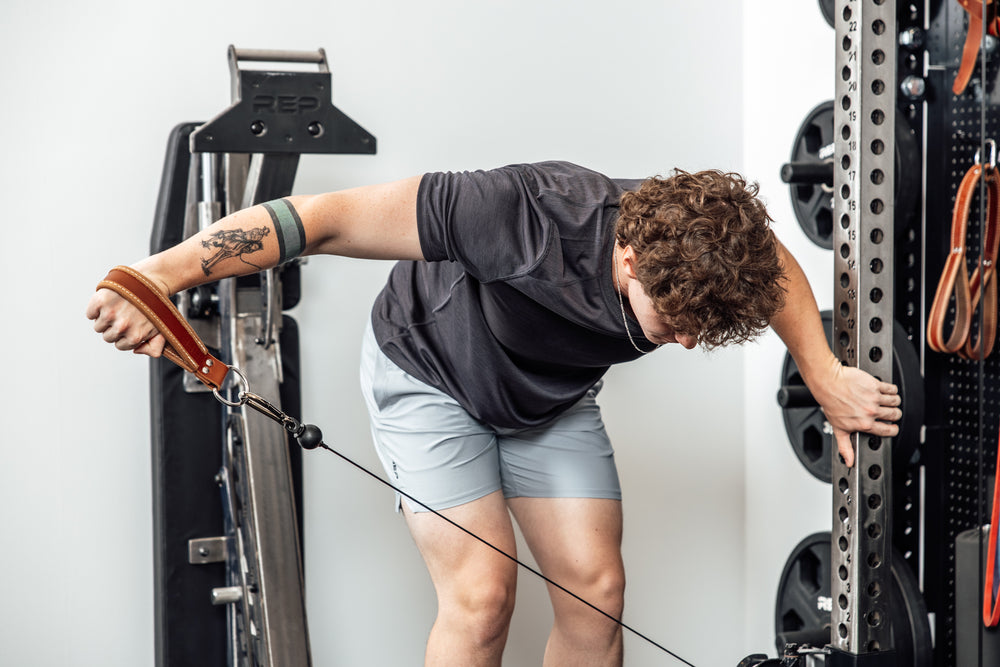 An athlete working out with a REP USA Leather Single Handle Cable Attachment in Brown on a cable machine