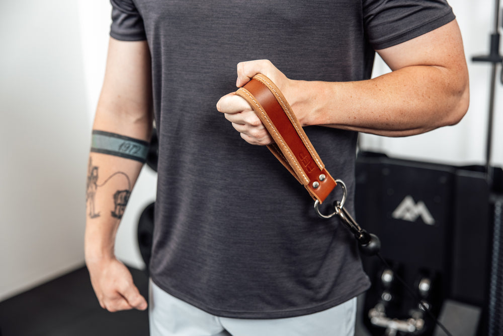 An athlete performing single arm cable curls REP USA Leather Single Handle Cable Attachment in Brown