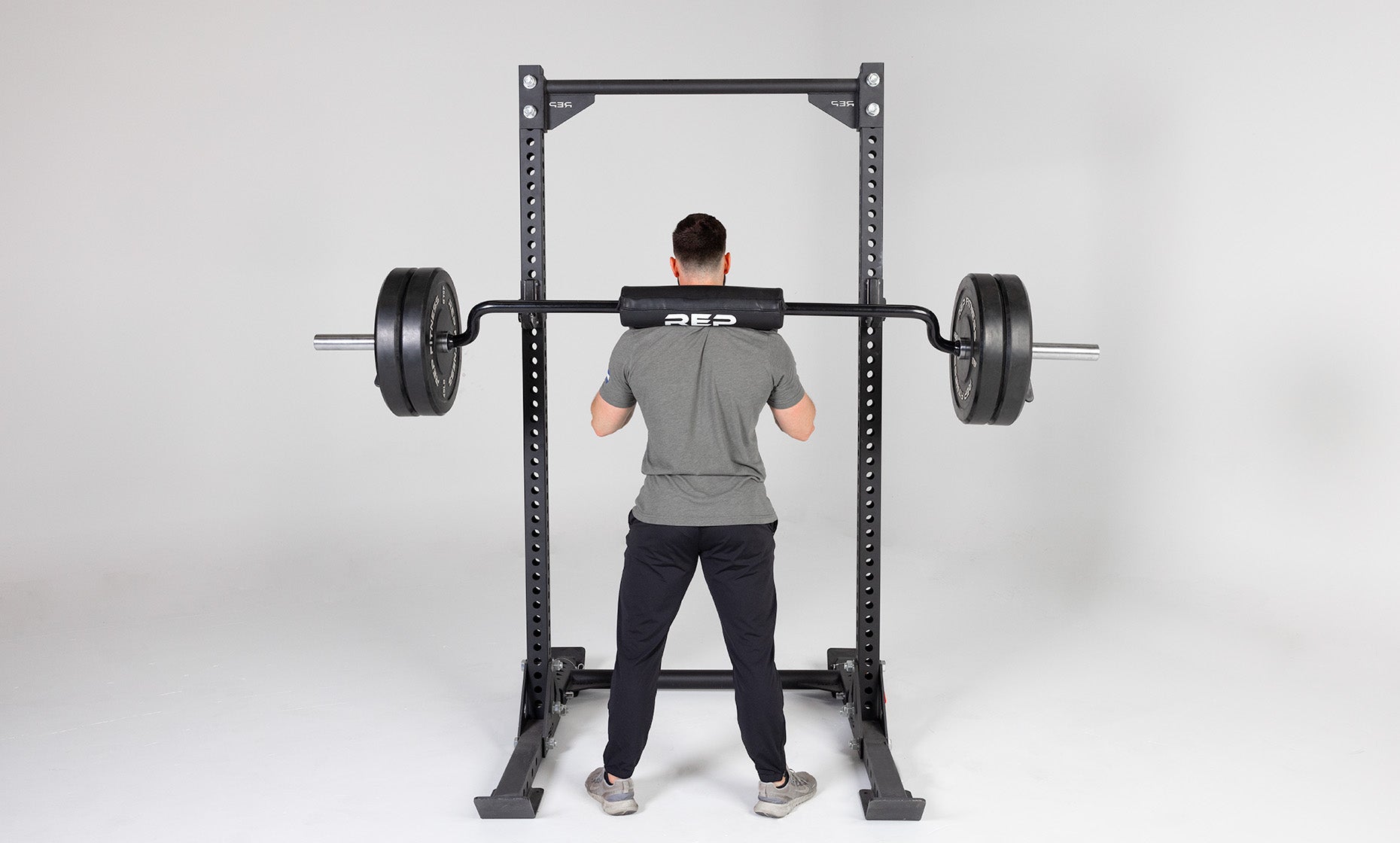 Lifter with a loaded Safety Squat Bar at the top of a squat outside of a REP Yoke.