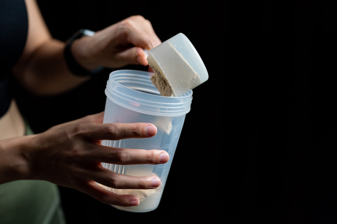 Woman scooping protein powder into a shaker bottle