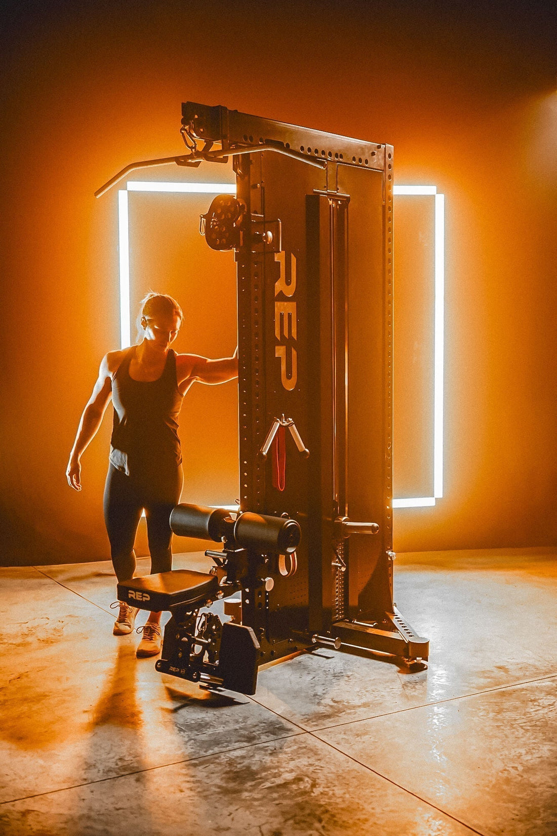 An athlete walks around a cable system backlit by orange LEDs.