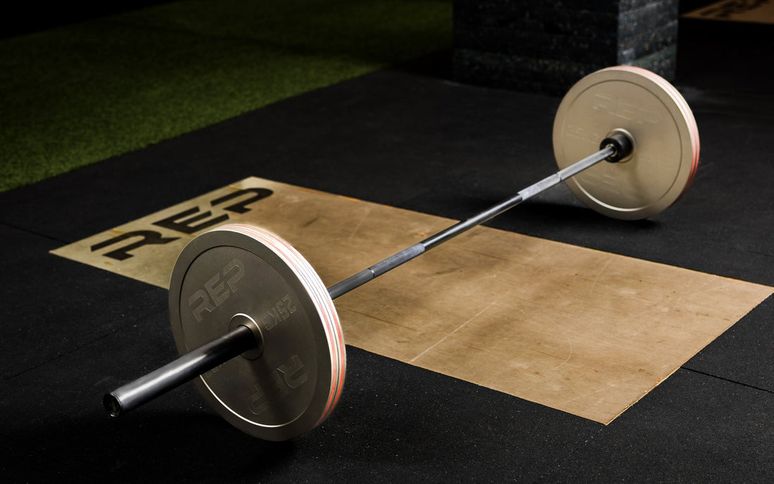 A loaded barbell sits on a deadlift platform in a gym.