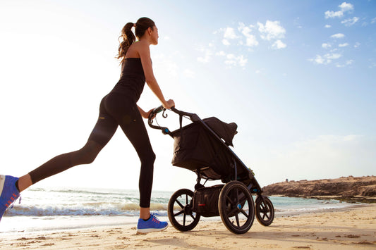 Athlete runs on the beach pushing a stroller.