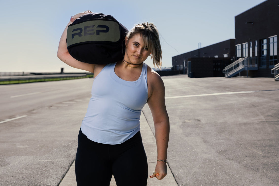 Athlete carries REP® Stone Sandbag over one