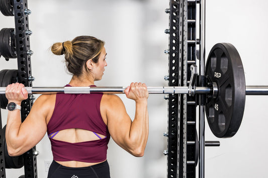 An athlete re-racks the weight with the REP® Smith Machine attachment.