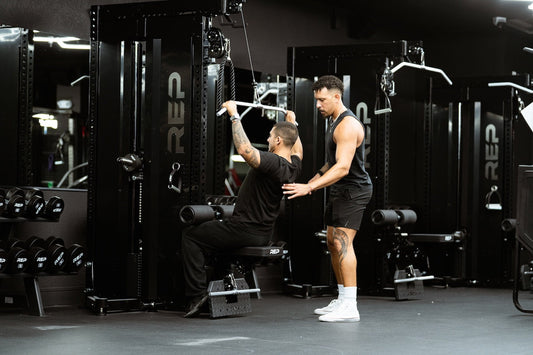 Athlete trains on REP equipment with a trainer.