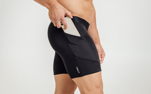 Side view of model sliding his iPhone into the side pocket of the REP Virtus Light Compression Shorts.
