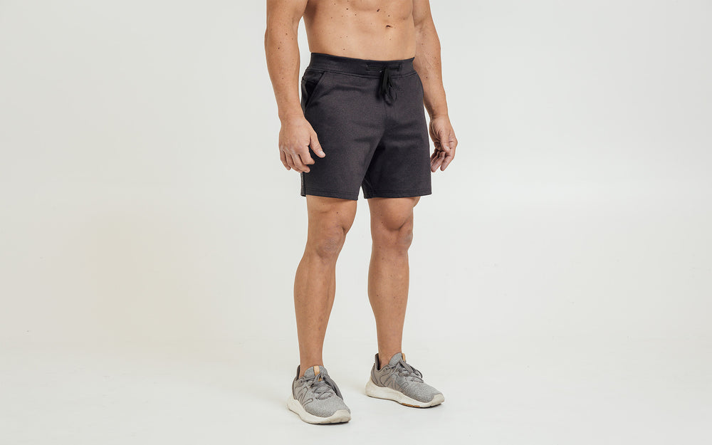 Front view of model wearing the heather black REP Versa Shorts.