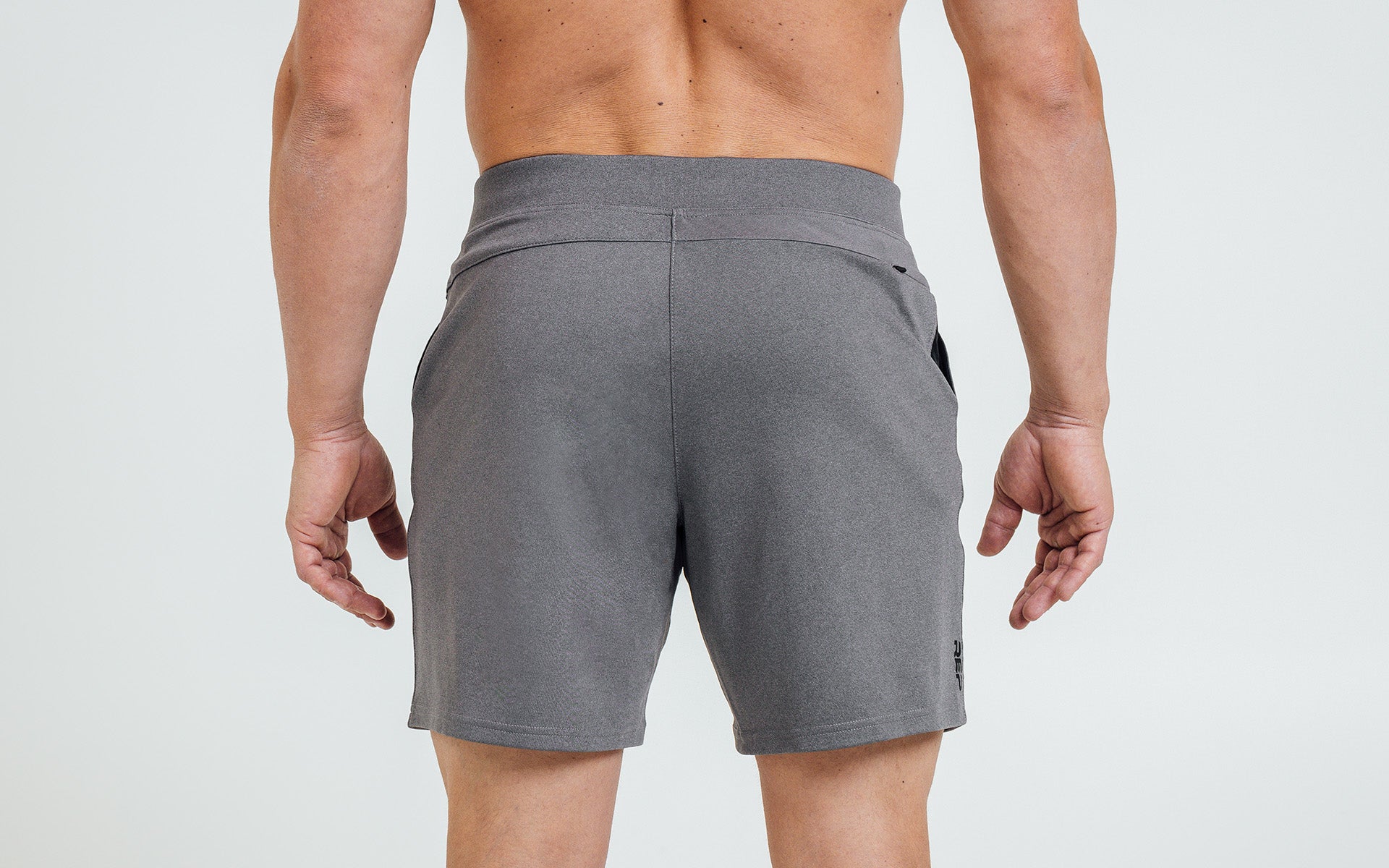 Back view of model wearing the heather cool gray REP Versa Shorts.