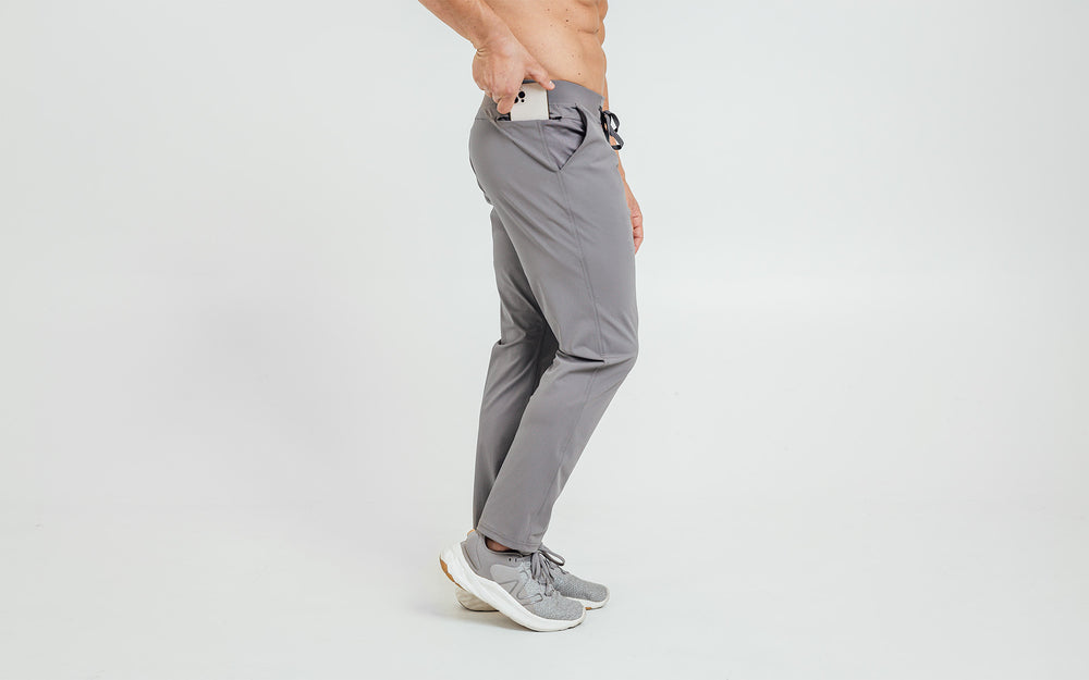 Side view of model sliding his iPhone into the side hip pocket of the cool gray REP Felix Pants.