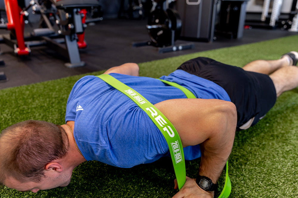 Athlete using a green Latex-Free Pull-Up Band for assistance while performing push-ups.