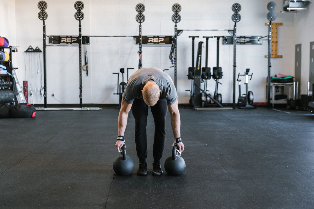 Lifter securing his REP Lifting Straps to kettlebell handles.