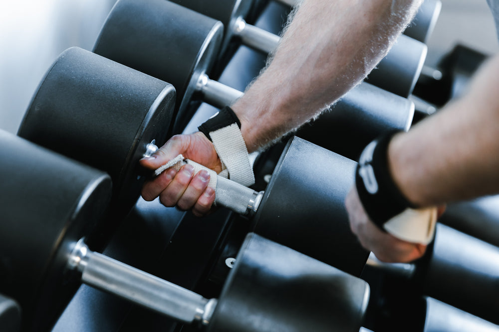 Lifter securing his REP Lifting Strap to the handle of a heavy dumbbell.