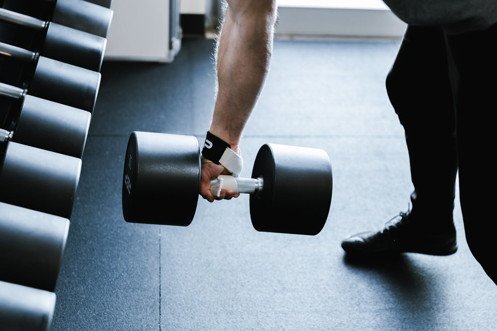 Lifter performing a single arm bent over row while wearing a REP Lifting Strap.