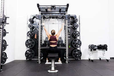 Person using the Ares™ 2.0 for lat pulldowns on the Summit™ All-In-One Ares™ 2.0 Wall-Mounted configuration in a gym setting.