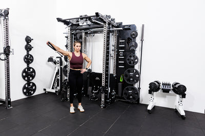 Person using the Ares™ 2.0 for cable side raises on the Summit™ All-In-One Ares™ 2.0 Wall-Mounted configuration in a gym setting.