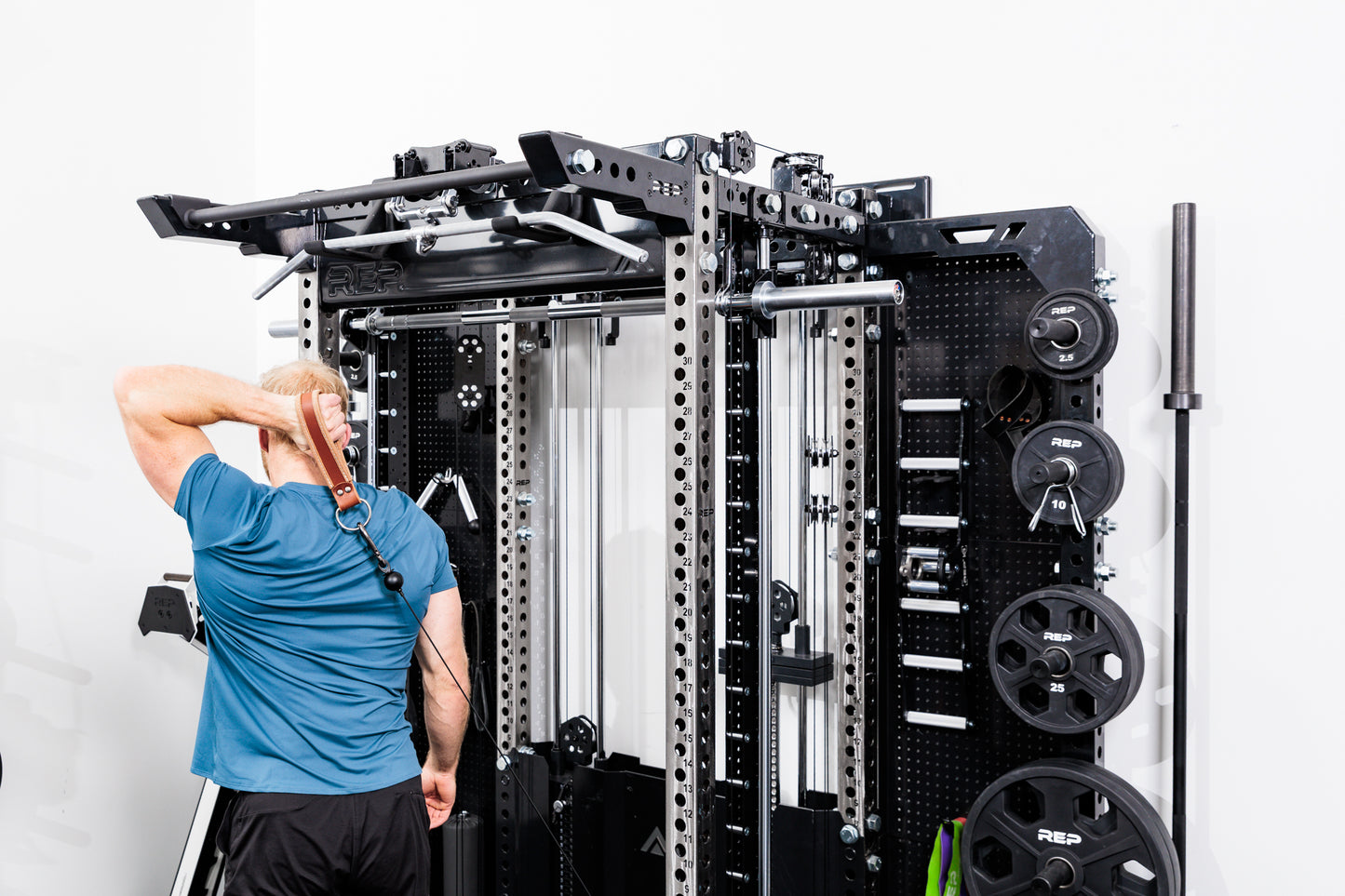 Person using the Ares™ 2.0 for cable machine exercises on the Summit™ All-In-One Ares™ 2.0 Wall-Mounted configuration in a gym setting.