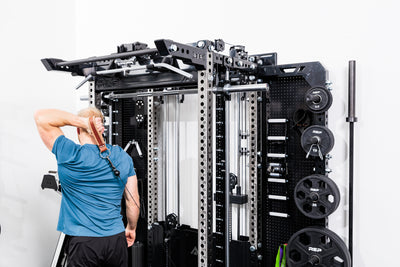 Person using the Ares™ 2.0 for cable machine exercises on the Summit™ All-In-One Ares™ 2.0 Wall-Mounted configuration in a gym setting.