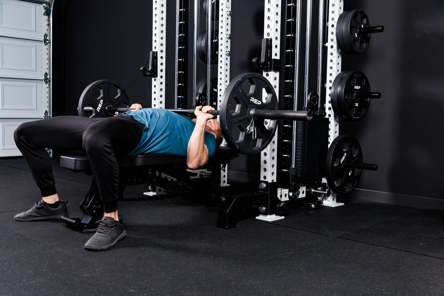 Person performing bench press with a barbell and weights on the Summit™ All-In-One Athena™ .