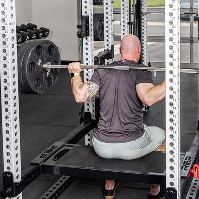 A REP Fitness Utility seat attached to the Flip-Down Safeties 2.0 being used for box squats