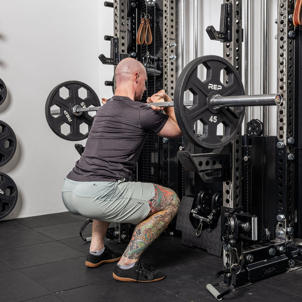 Athlete doing front squat with the short Spotter Arms 2.0 below the bar