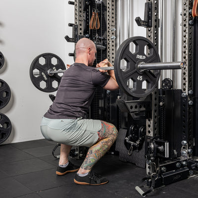 Athlete doing front squat with the short Spotter Arms 2.0 below the bar