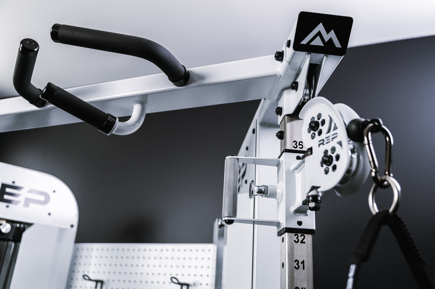 Image showing the mountain logo on the endcap, trolley, and one half of the multi-grip pull-up bar on the top of the white version of Arcadia™ max