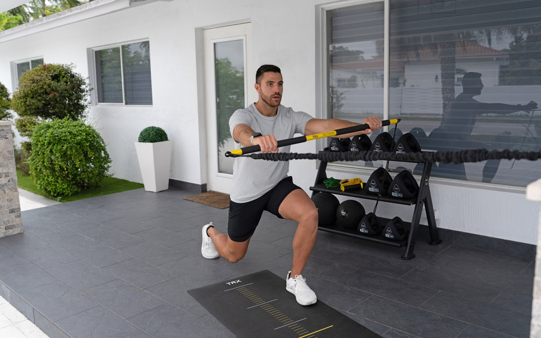 Front shot: Athlete performing a split squat with the TRX® Rip Trainer™ at shoulder height in front of them