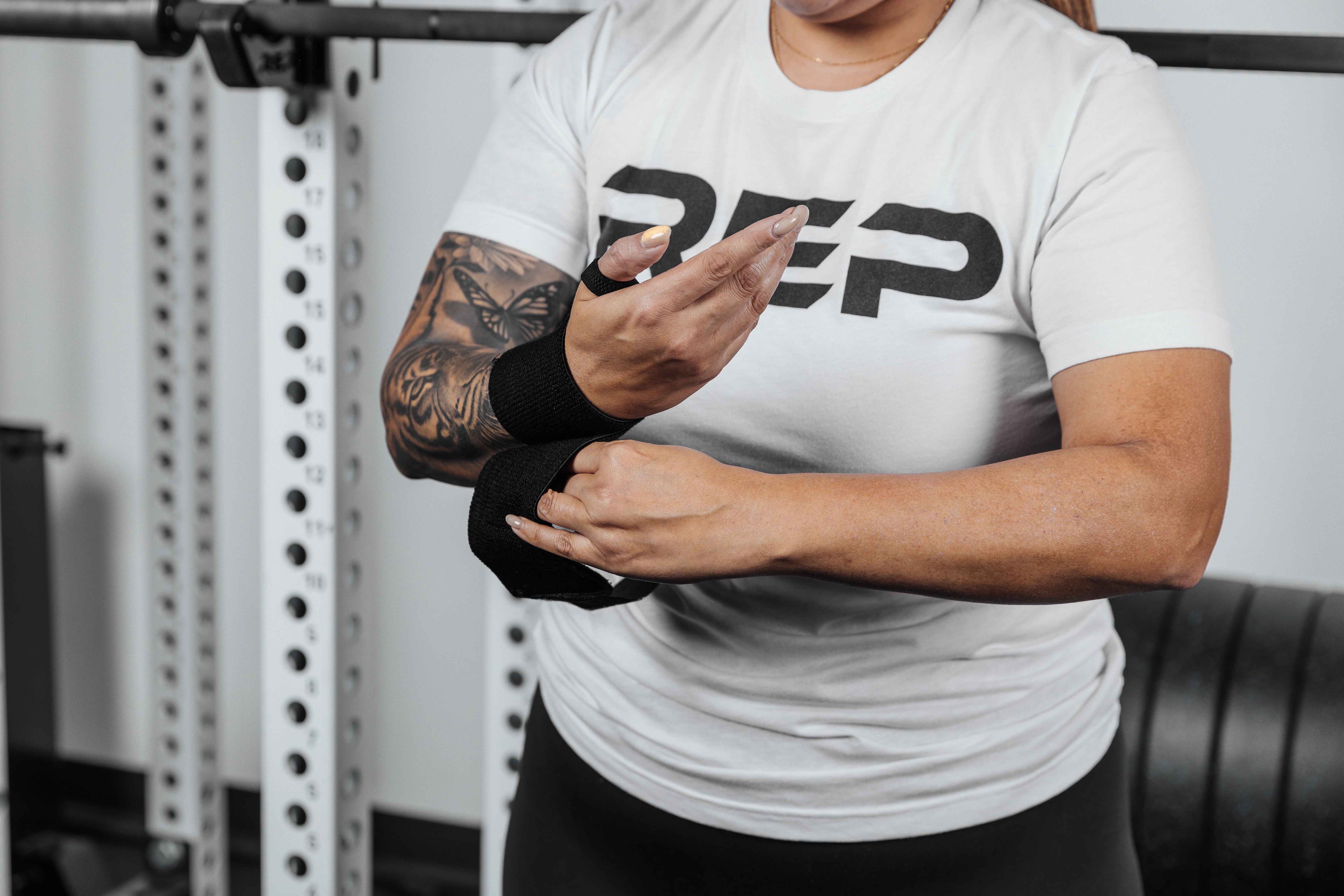Close up shot of an athlete securing the hook and loop closure of the REP Wrist Wrap around their wrist for a secure fit