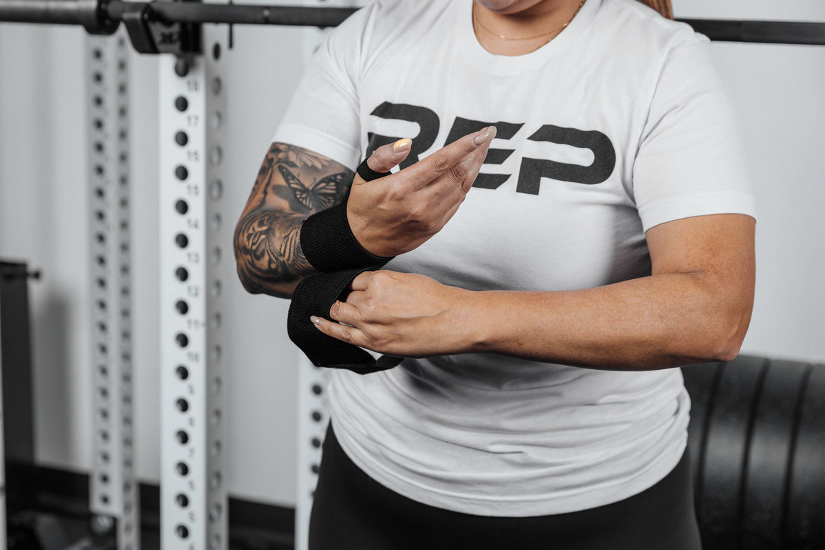 Close up shot of an athlete securing the hook and loop closure of the REP Wrist Wrap around their wrist for a secure fit