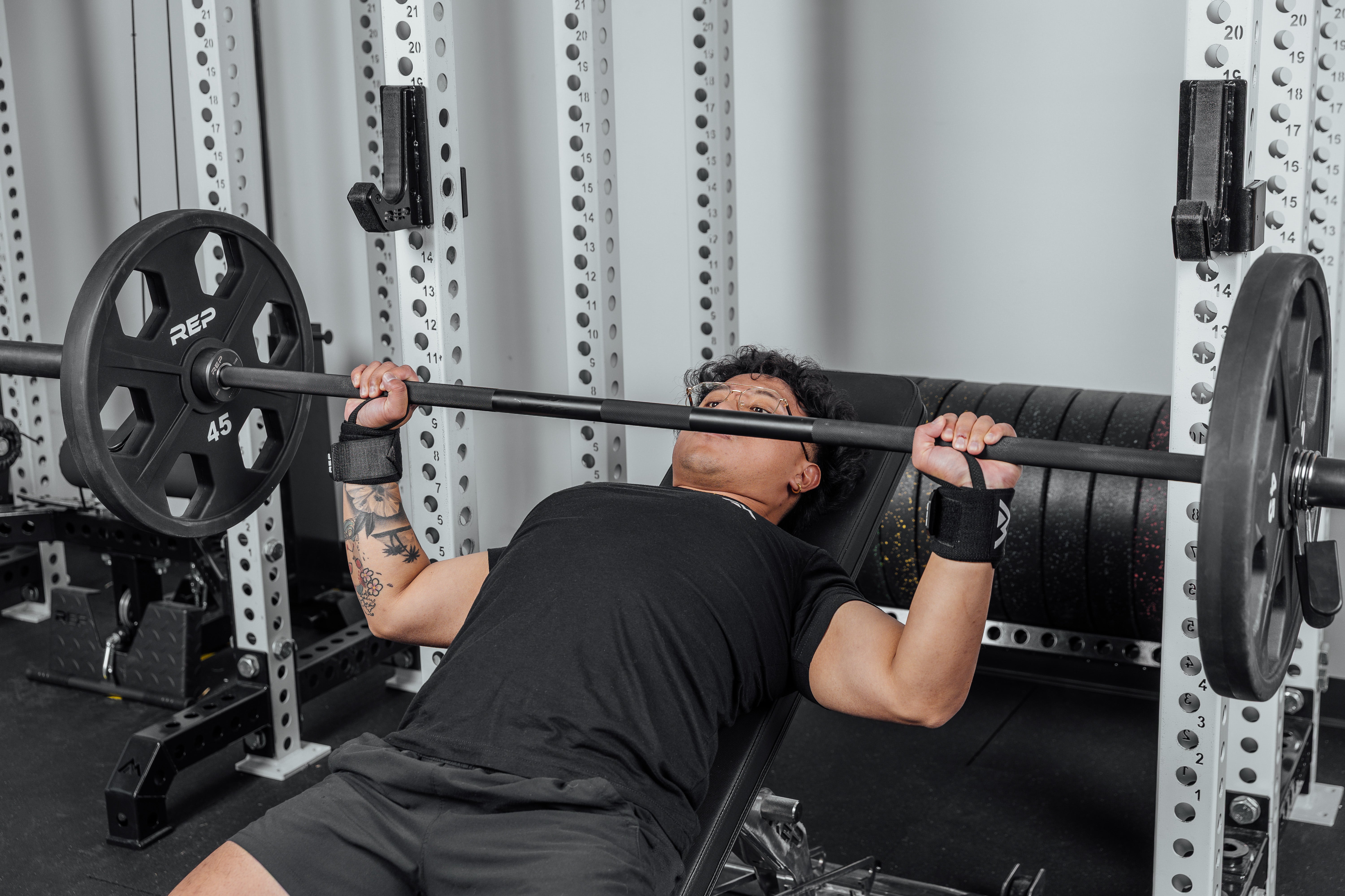 Front shot of an athlete's wrists being supported by the REP Wrist Wraps while pressing a loaded barbell