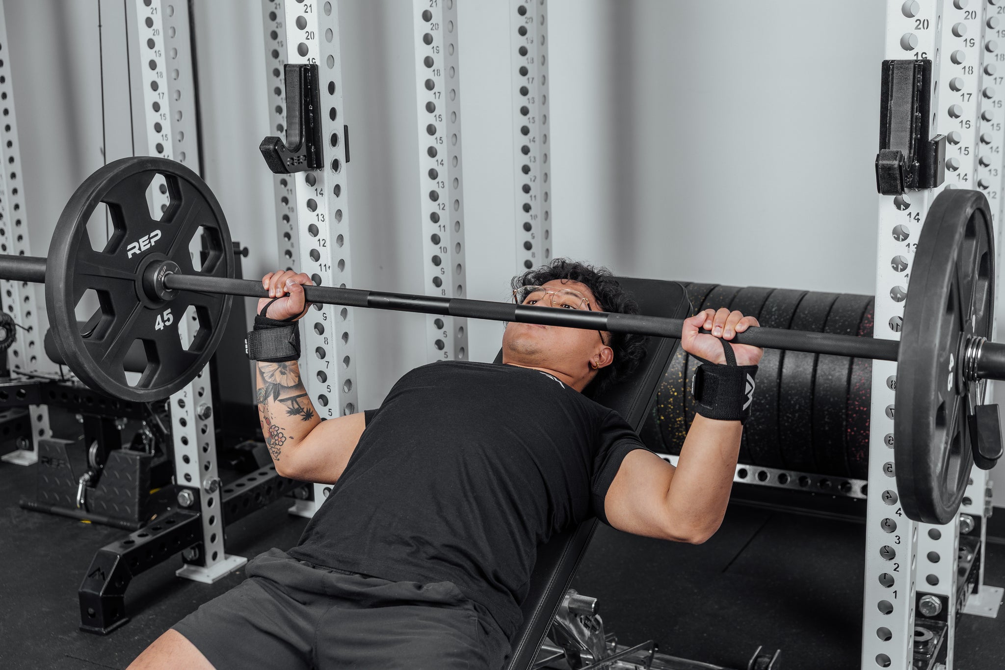 Front shot of an athlete's wrists being supported by the REP Wrist Wraps while pressing a loaded barbell