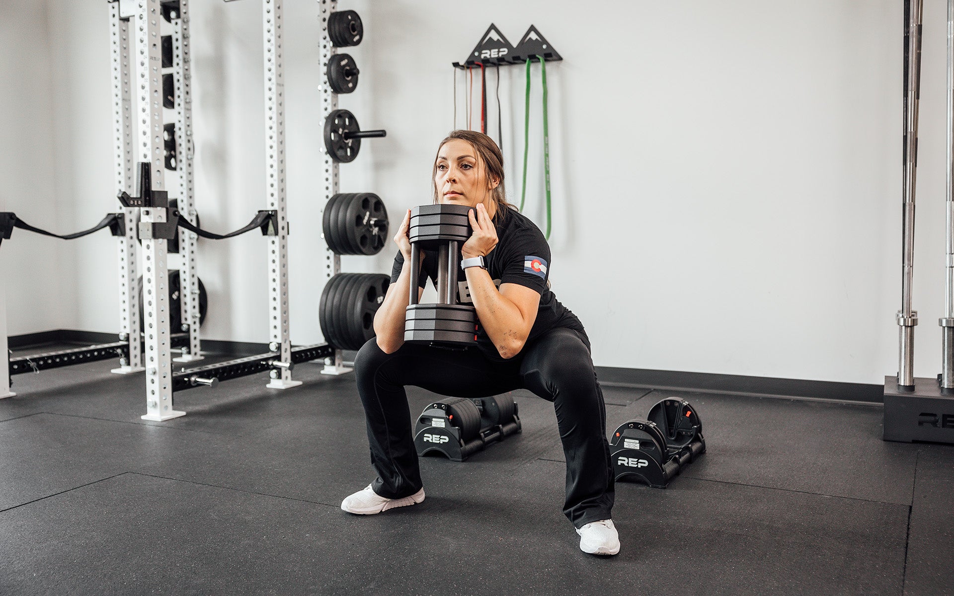 Female lifter performing a goblet squat with a single REP Fitness QuickDraw Adjustable Dumbbell.
