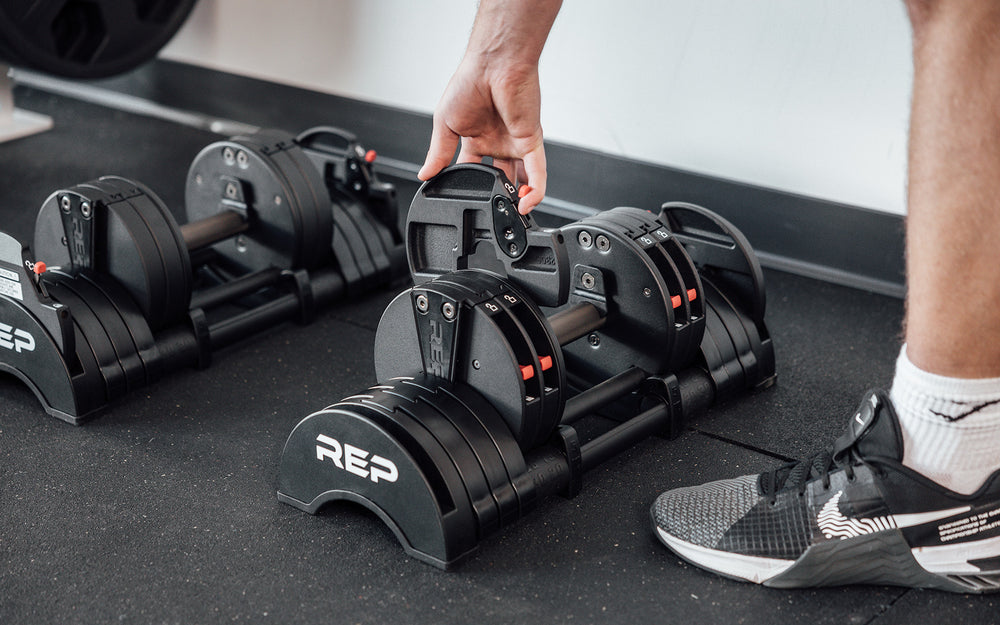 Close-up view of a lifter adding on a 1.25kg microplate to a 15kg REP Fitness QuickDraw Adjustable Dumbbell (KG).