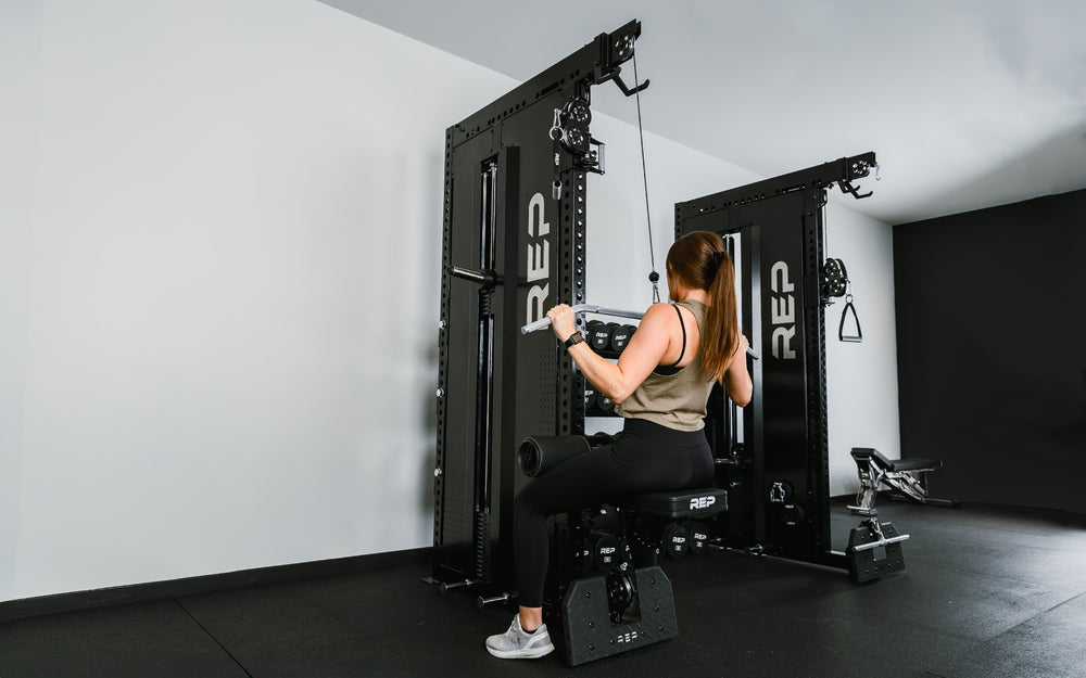 Outside angle of woman doing lat pulldowns on a single Adonis™ in a dual Adonis™ with Storage setup.