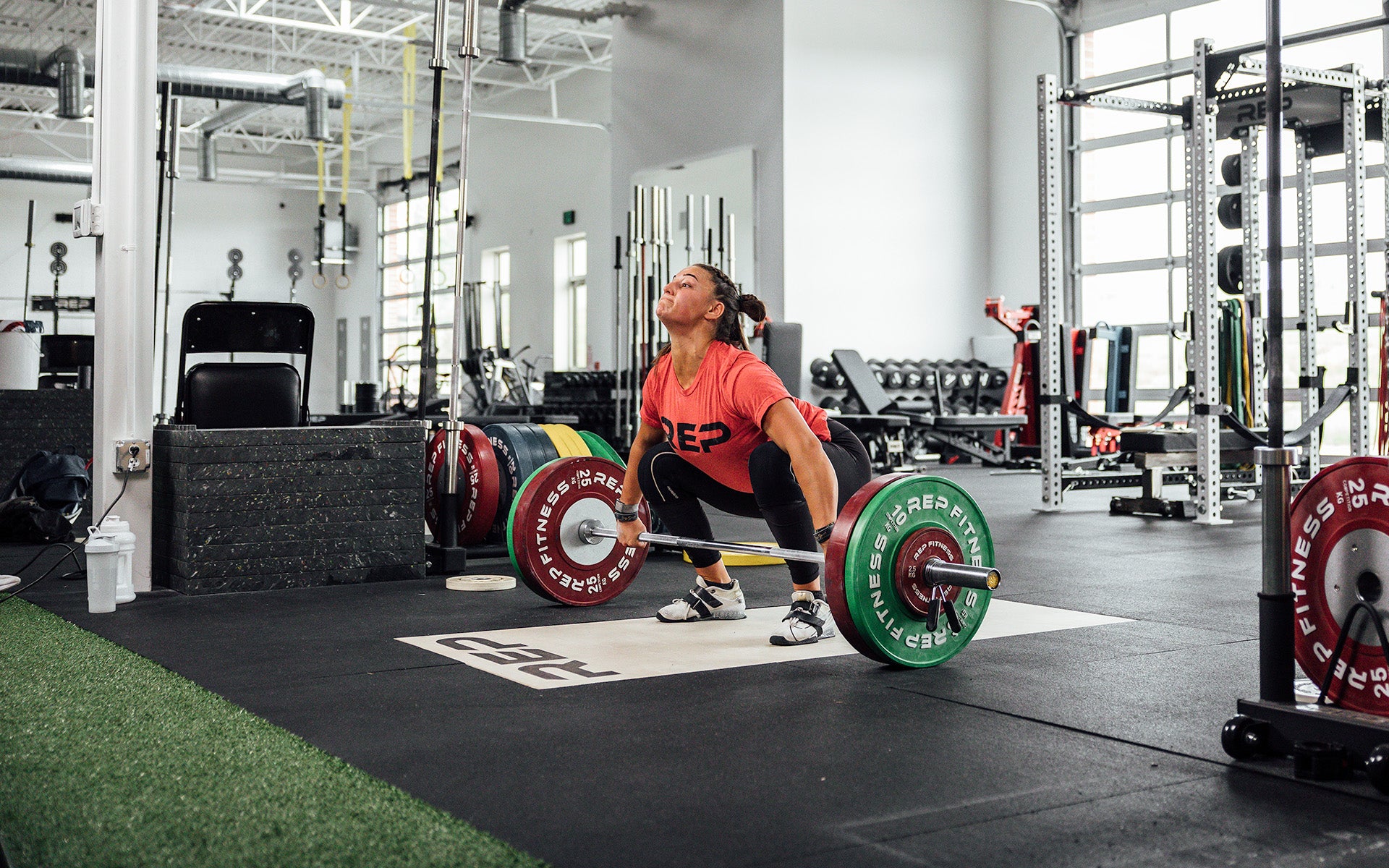 Female lifter set up for a lift on an Olympic lifting platform using REP's 15kg Alpine Weightlifting Bar.