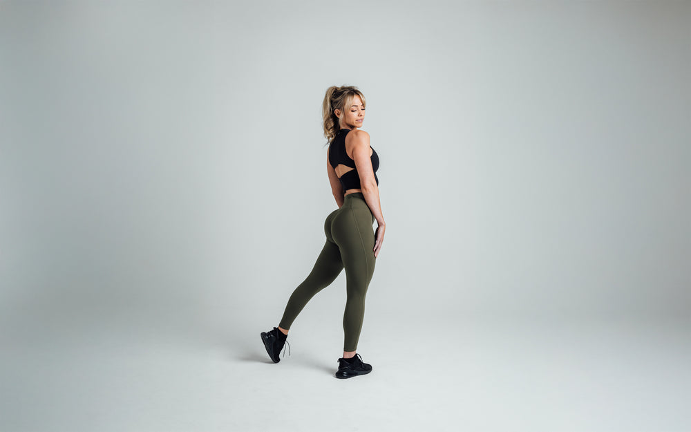 Side shot of an athlete striking a pose while wearing the REP Rhea Tank in Black.