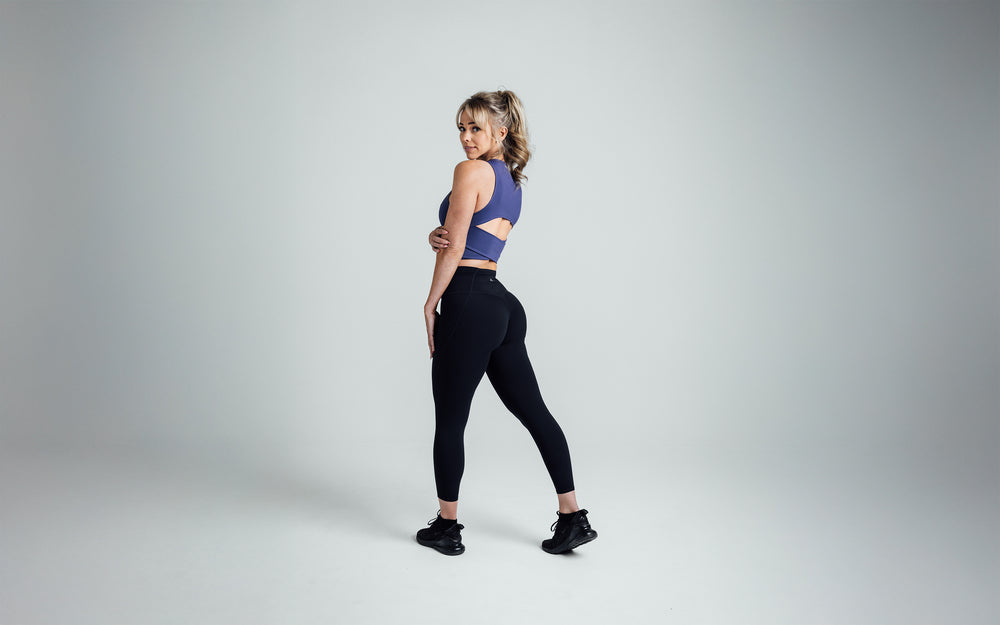 Side shot of an athlete striking a pose while wearing the REP Rhea Tank in Dusk.