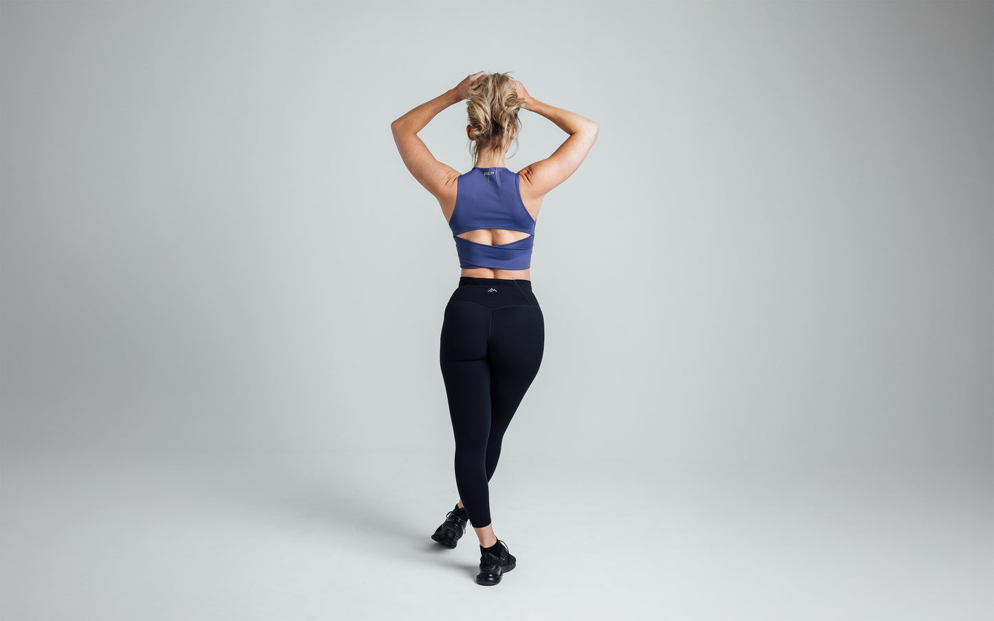 Athlete stretching her arms above her head while wearing the REP Rhea Tank in Dusk