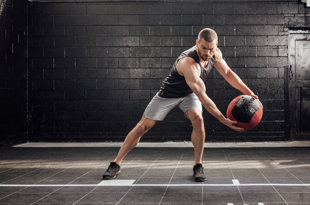 Athlete throwing a med ball wearing Heather Black Sigmatech Tank Top