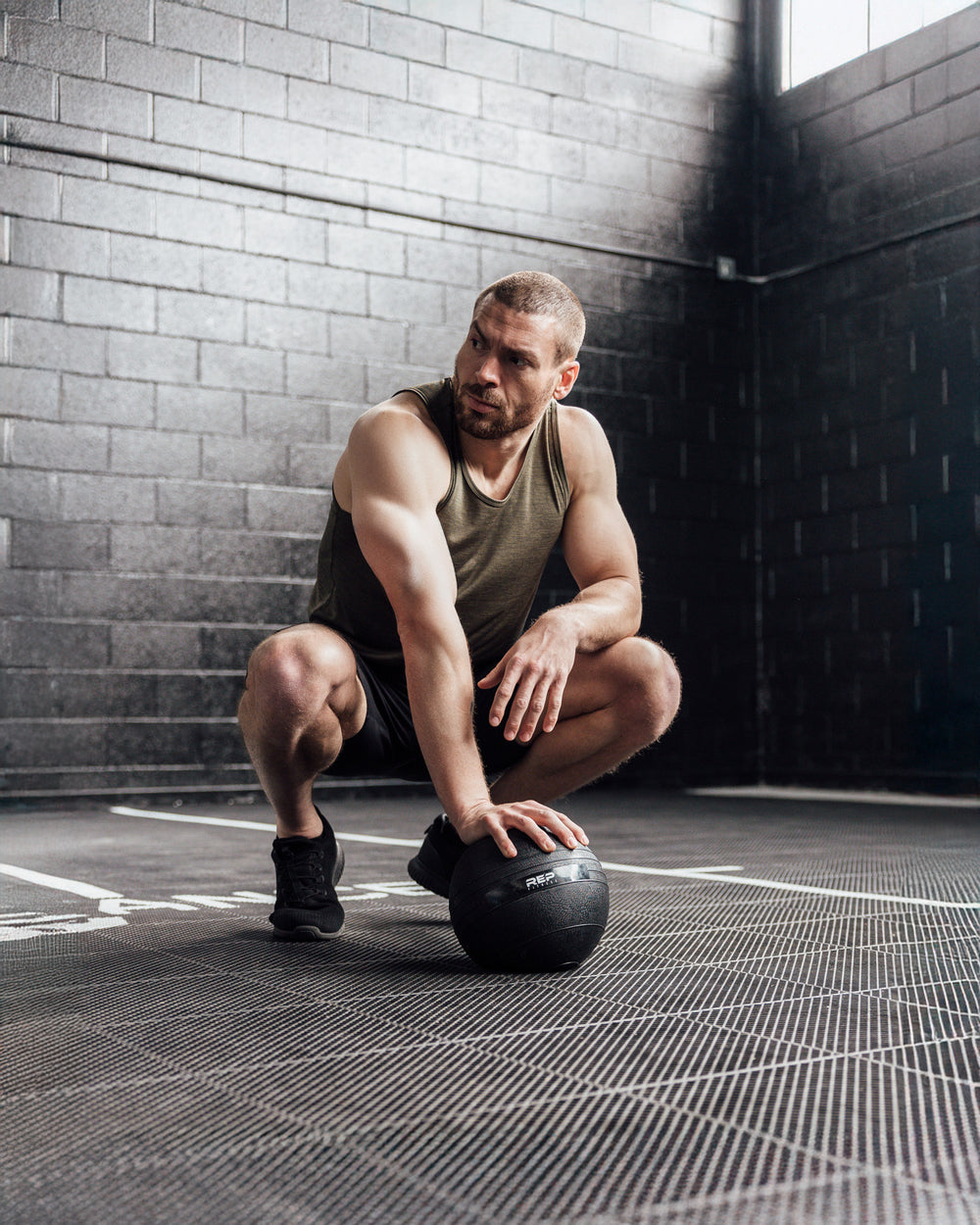 Athlete crouched wearing Heather Olive Sigmatech Tank Top