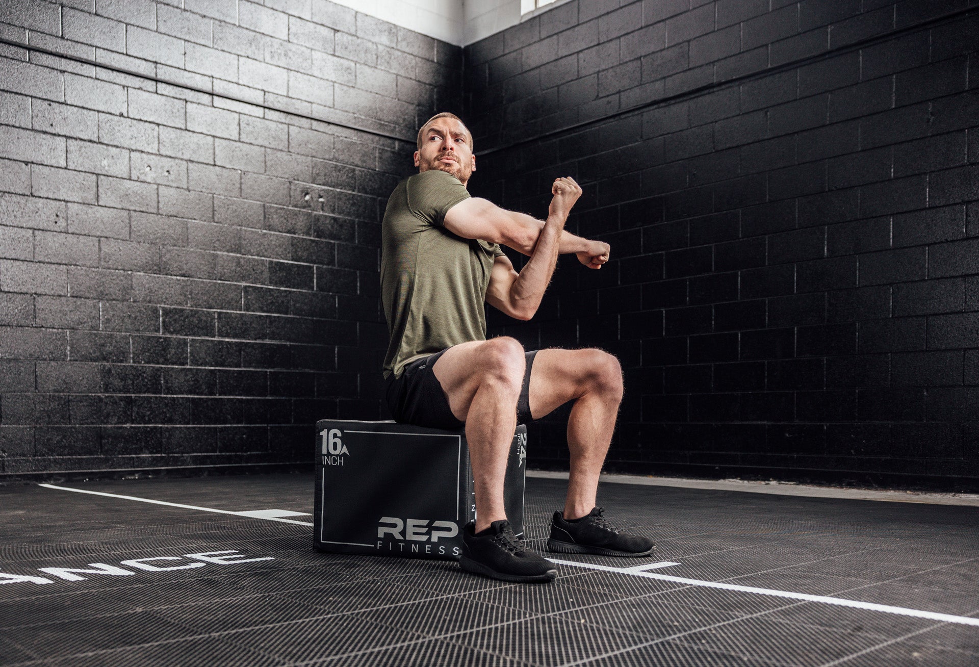 Athlete stretching in a Heather Olive Sigmatech Shirt. Also available in Heather Navy, Heather Black.
