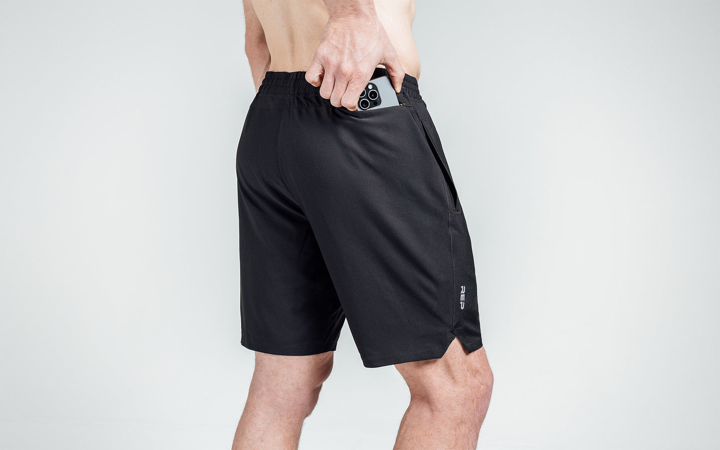 Athlete putting a phone in the zipper pocket of Black Motus Shorts