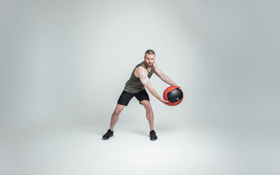 Athlete wearing Black Men's Motus Shorts holding a med ball