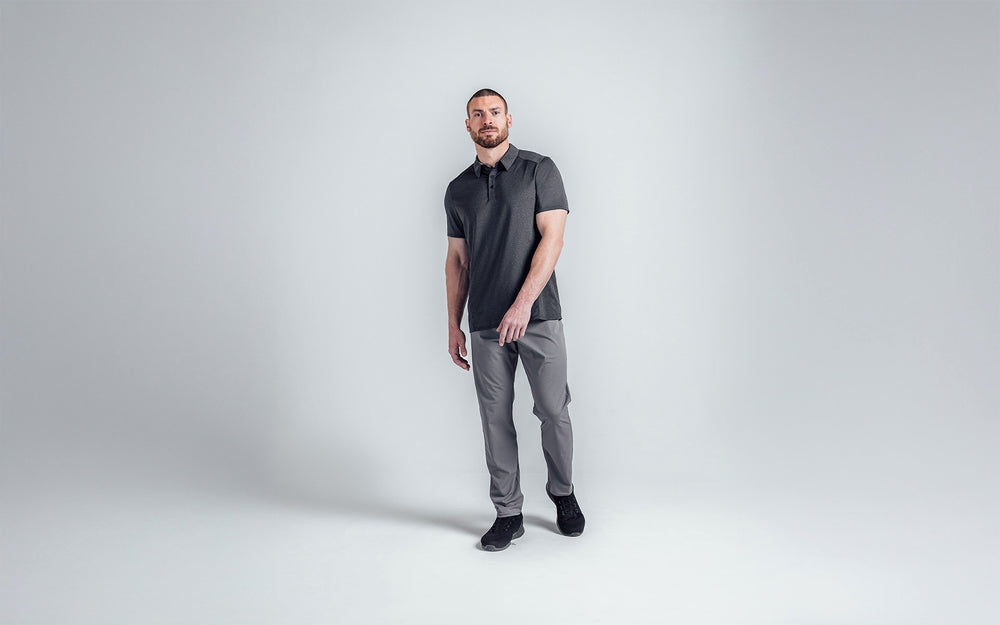 A posed front shot of an athlete wearing the REP Audax 
Polo in Heather Black. The forward shoulder seams and 
angled side seams create an athletic look, visually slim 
waist, and accentuate shoulders