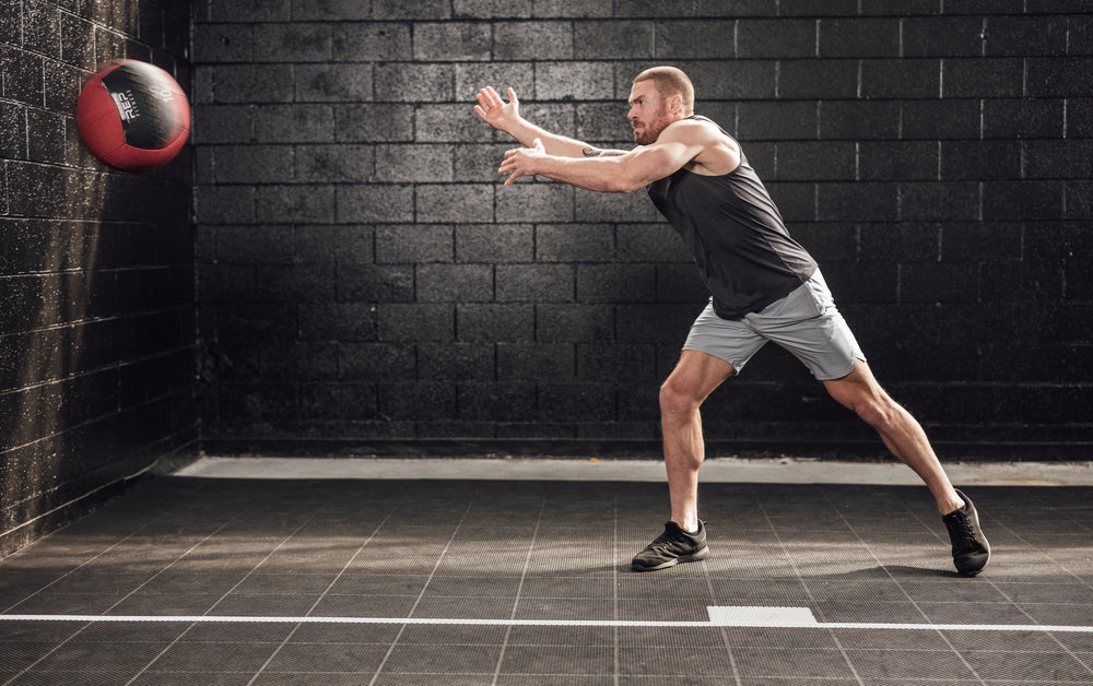 Athlete throwing a med ball wearing silver Men's Motus Shorts