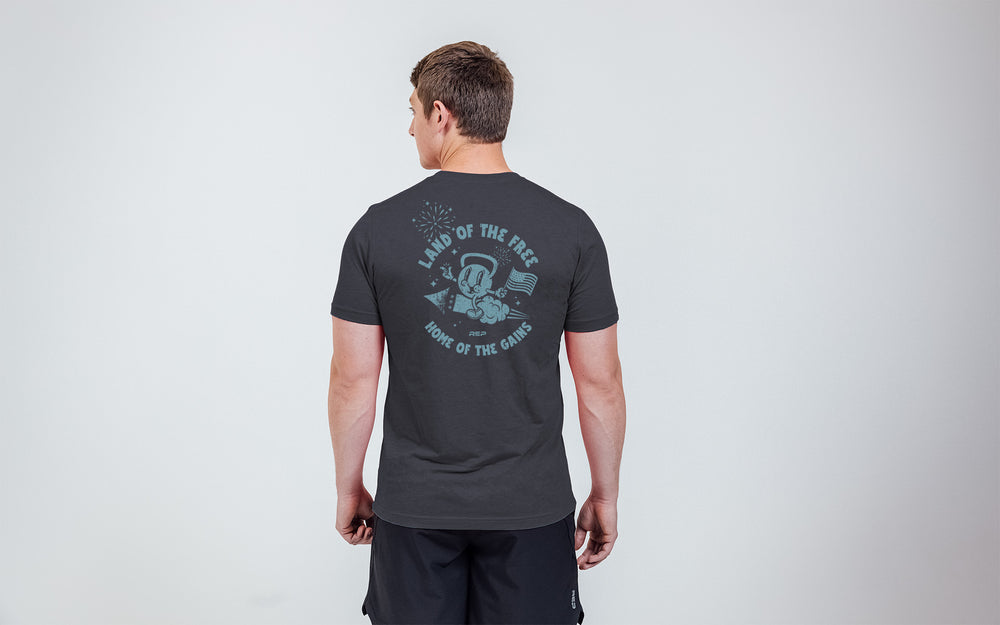 Model posing with a back view of the REP Men's Liberty Bell Tri-Blend Crew T-Shirt in Black and graphic in Blue